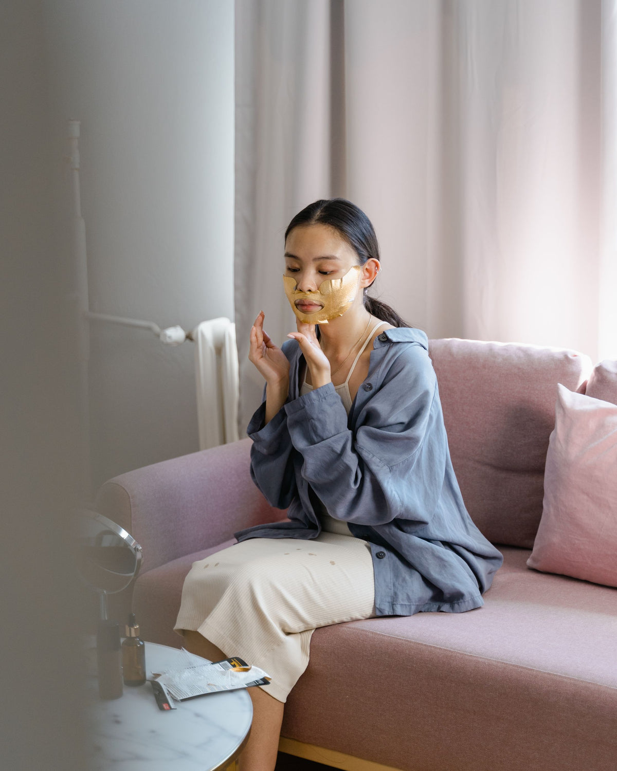 Chica asiática aplicándose una mascarilla facial en casa como parte de su rutina de cuidado de la piel