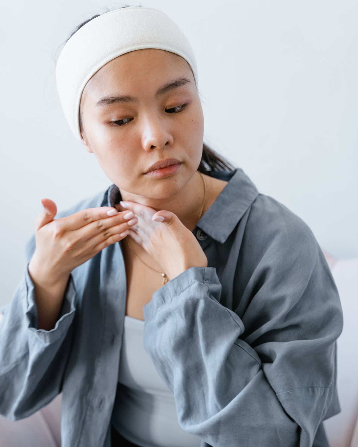 Chica asiática aplicándose un producto hidratante en el cuello y el rostro